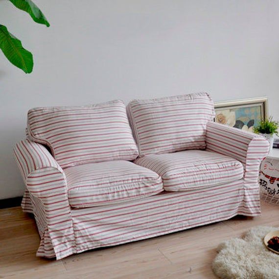 a living room with a striped couch, rug and potted plant on the floor