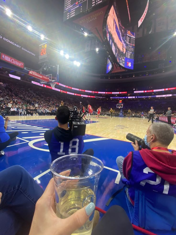 a person taking a photo with their cell phone at a basketball game in an arena