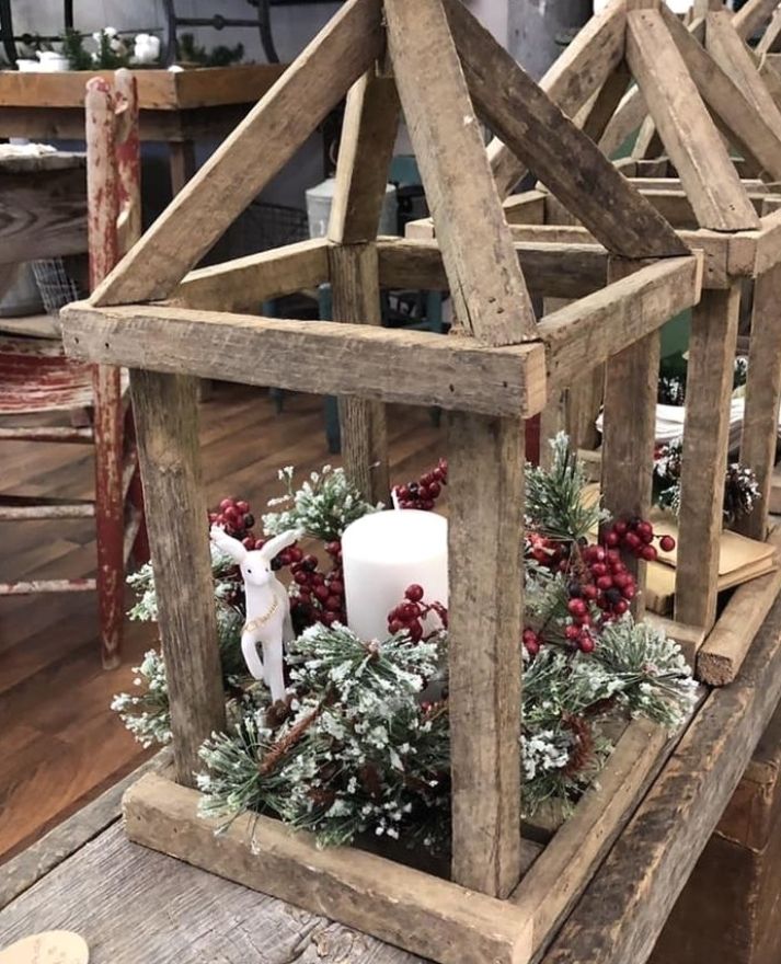 a wooden lantern with candles and greenery in it on a wood table next to other items