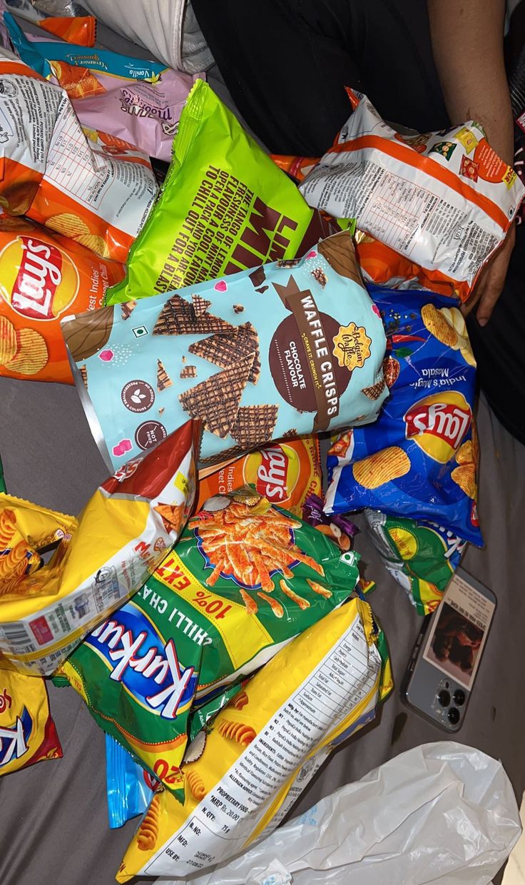 a pile of chips sitting on top of a bed next to a bag of chips