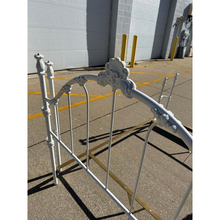 a white metal bed frame sitting on top of a parking lot