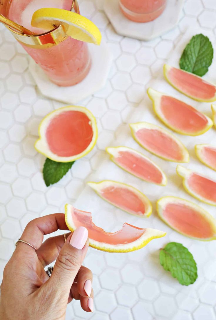 a person holding a grapefruit slice in front of some watermelon slices