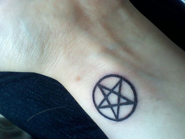 a small tattoo on the wrist of a person with a pentagramil in it