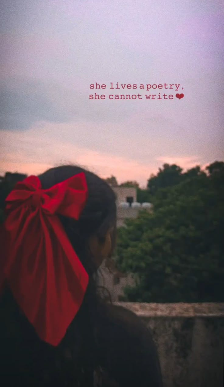 a woman with a red bow on her head looking out over the city at sunset