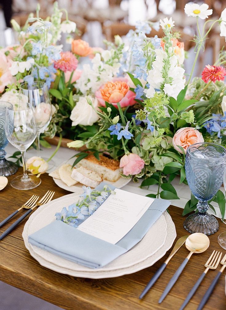 the table is set with blue and pink flowers