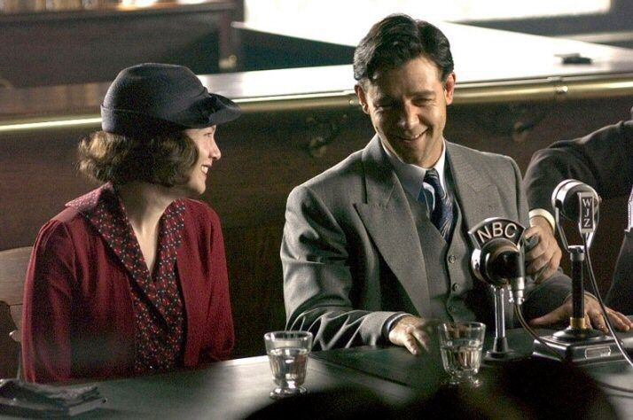 three people sitting at a table with microphones in front of them and one person wearing a hat