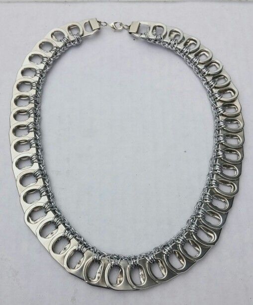 a silver necklace is displayed on a white surface