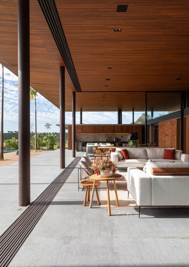 an outdoor living area with white couches and wooden ceilinging on the side of a building