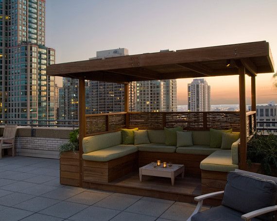 an outdoor seating area with couches and tables in front of the cityscape