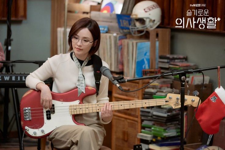 a woman sitting in front of a microphone while playing a guitar