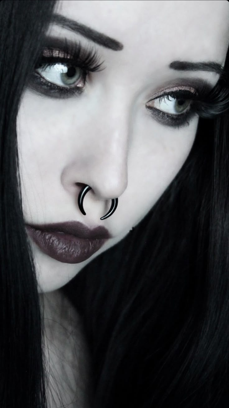 a woman with long black hair and piercings on her nose