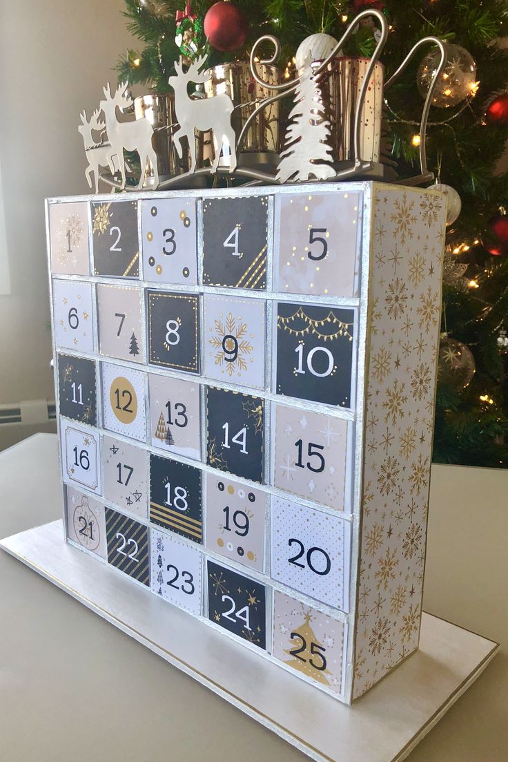 a christmas calendar sitting on top of a table next to a christmas tree with presents in it