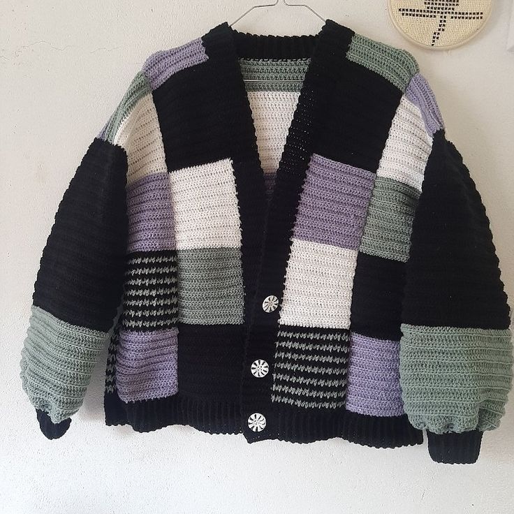 a knitted jacket hanging up on a wall next to a small white and black object