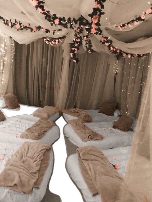 two beds covered in blankets and pillows under a canopy with flowers on the bedding