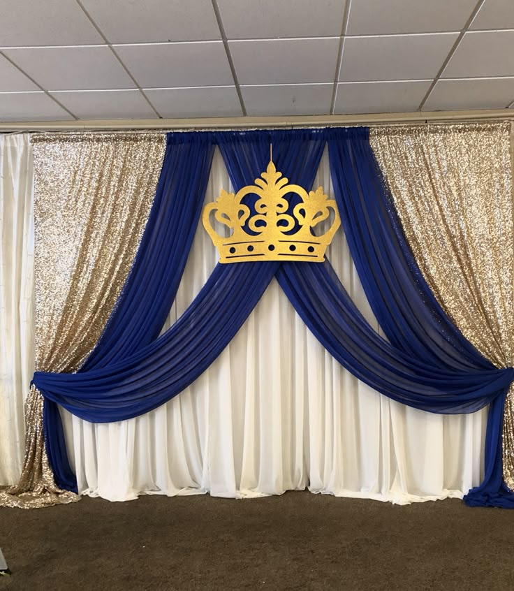 a blue and white curtain with a gold crown on it in front of a wall