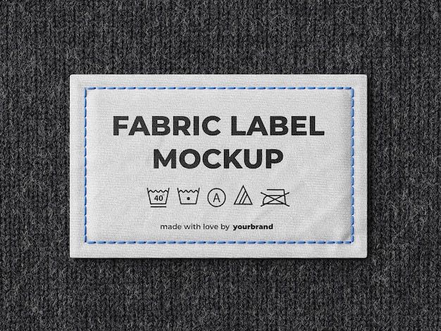 a label that says fabric label mockup on the side of a gray sweater with blue stitching