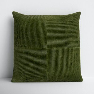 a green velvet pillow sitting on top of a white wall