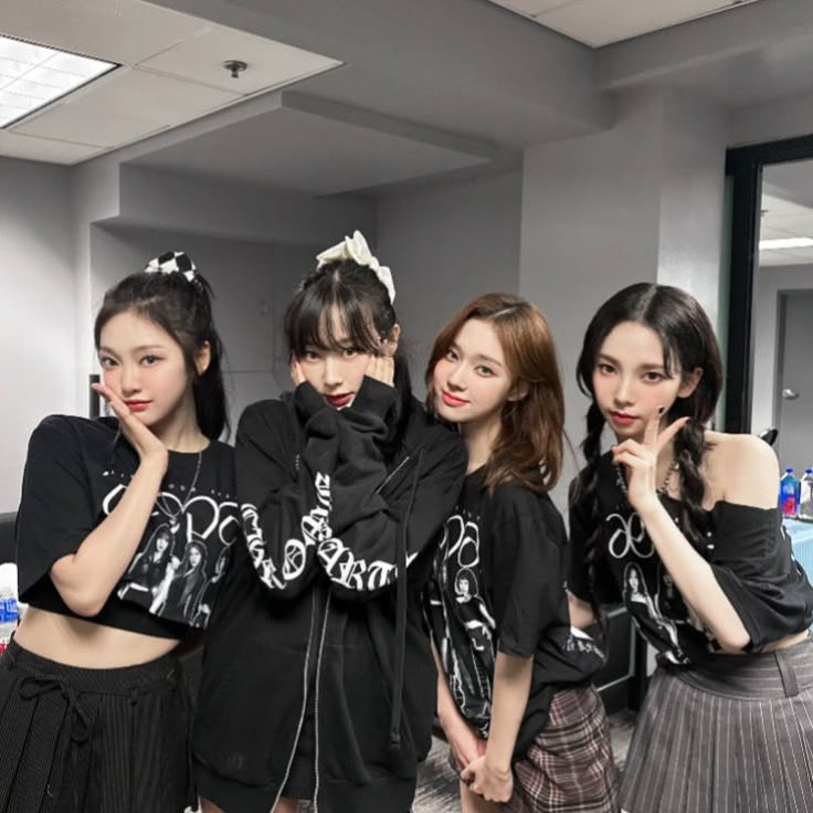 four young women standing next to each other in front of a mirror with their hands on their chins