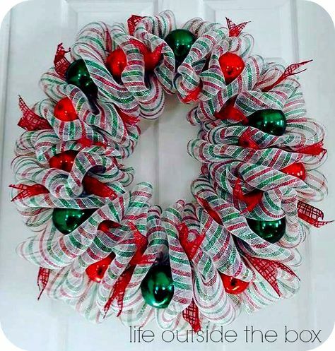 a christmas wreath made out of mesh and bells on the front door with words life outside the box written below