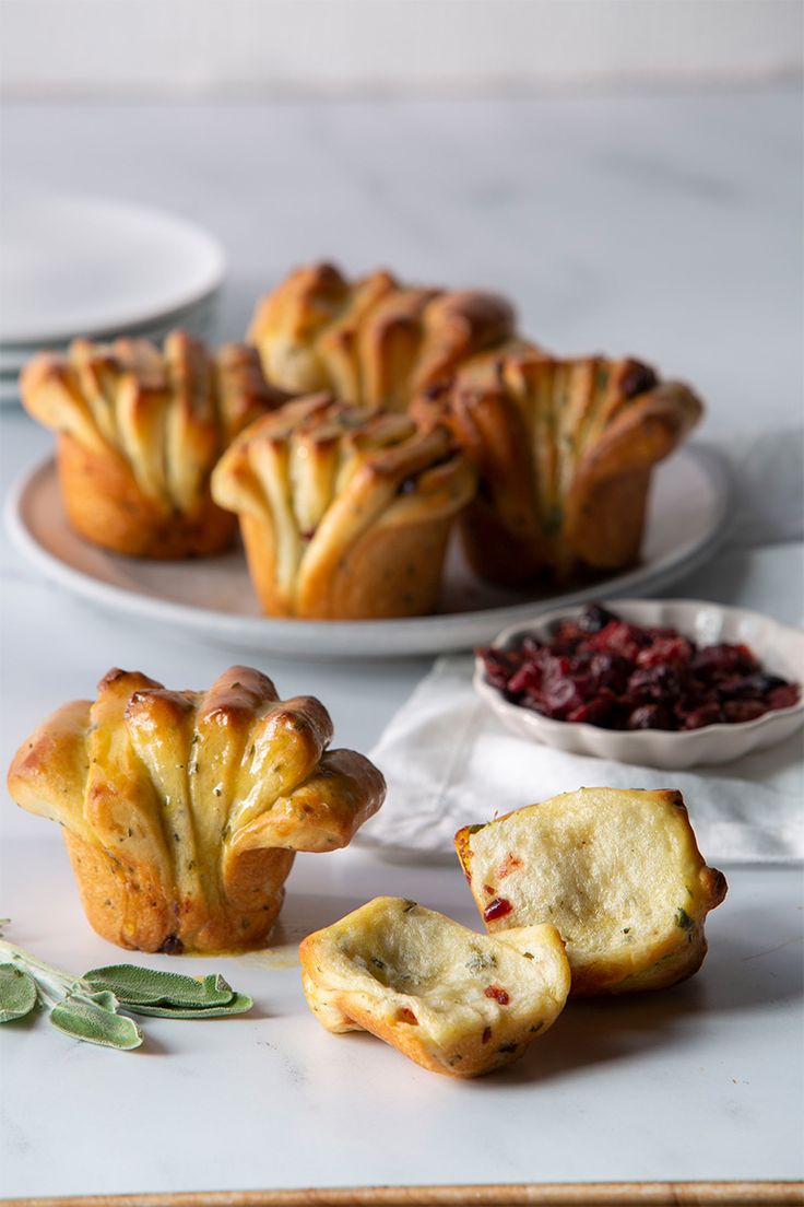 several pastries on plates with cranberry sauce and sage leaves next to them