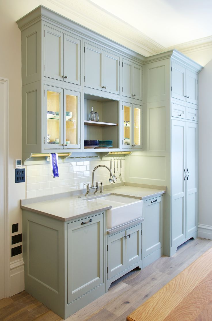 an empty kitchen with white cabinets and wood flooring, along with a wooden bench