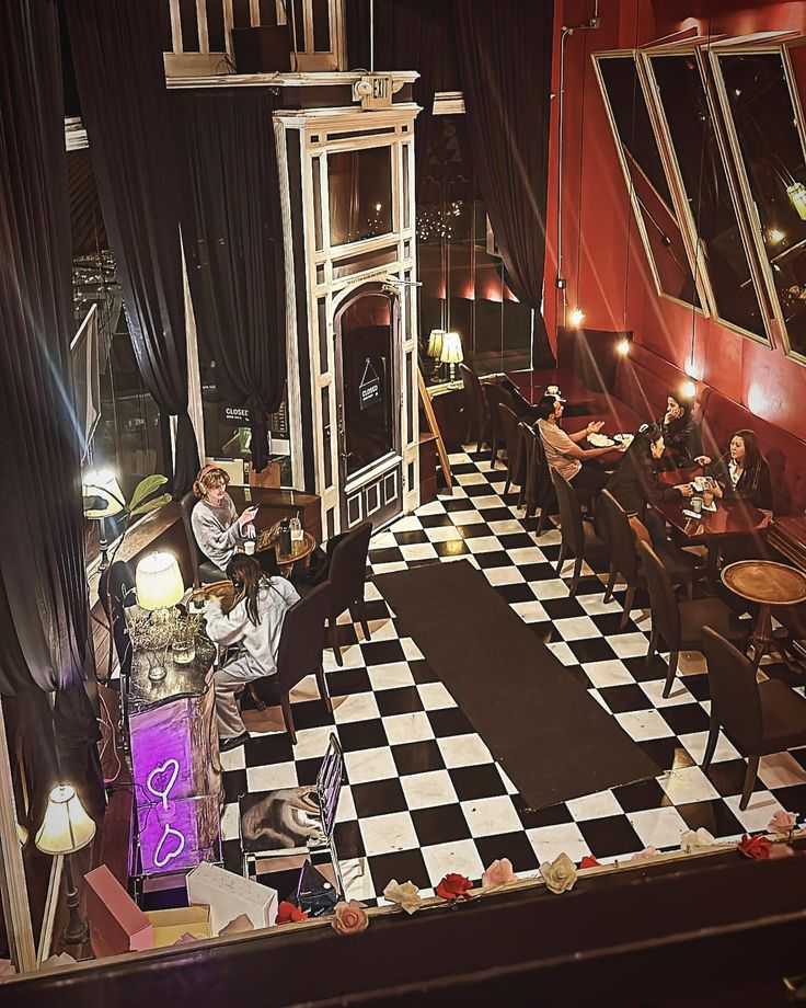 a room with black and white checkered flooring, two people sitting at tables