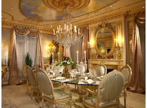 a fancy dining room with chandelier and table set for six people, all dressed in gold