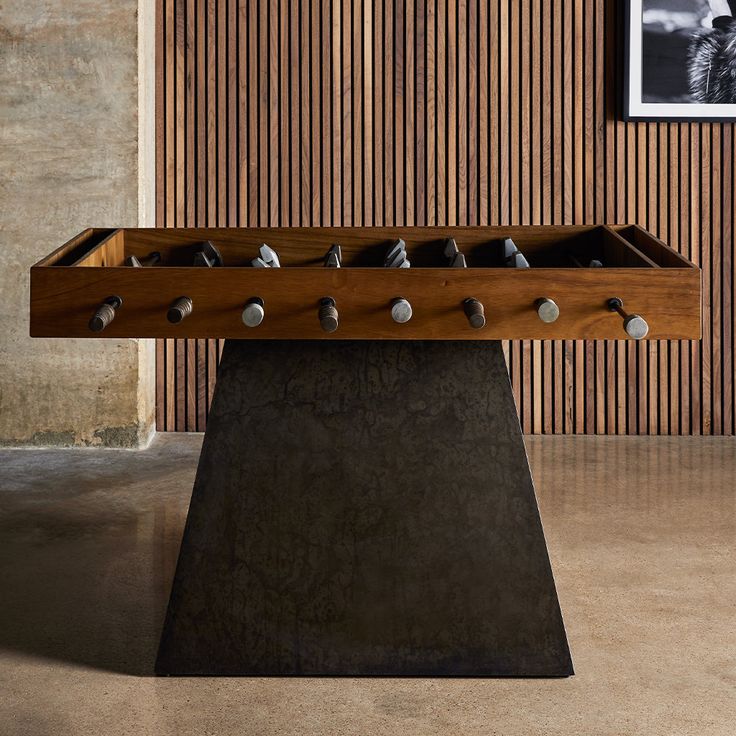 a wooden table with rocks on it in front of a striped wall and framed photograph