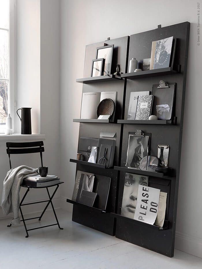 a black book shelf with pictures and books on it in front of a large window