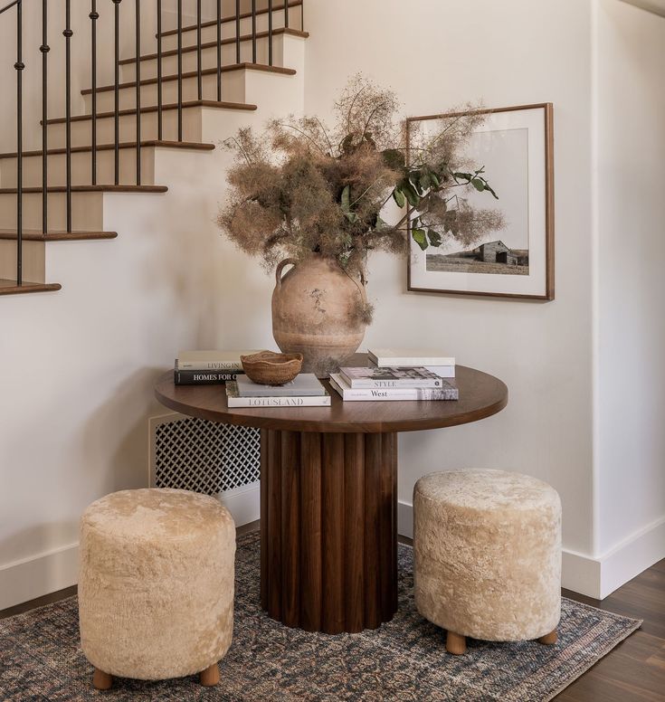 a table with two stools and a vase on it