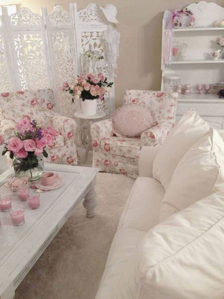 a living room filled with white furniture and pink flowers