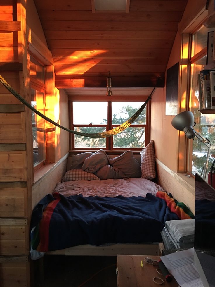 a small bedroom with a bed, window and ladder in the ceiling is made out of wood planks