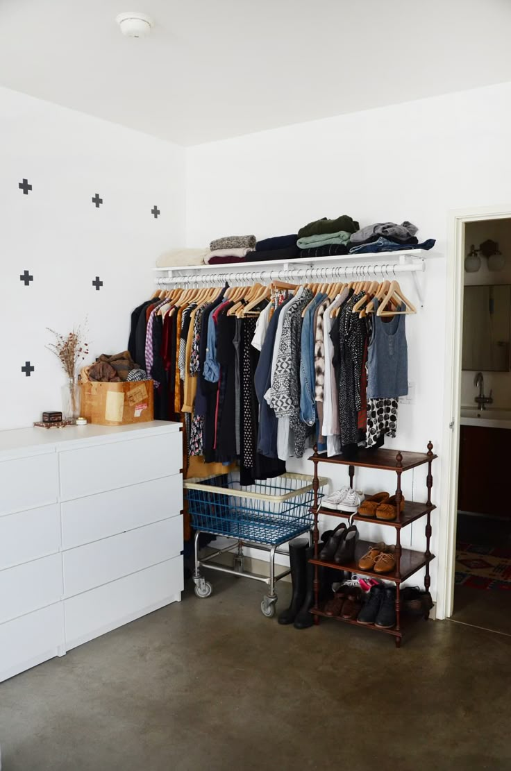 an organized closet with clothes and shoes hanging on the rack, next to a white dresser