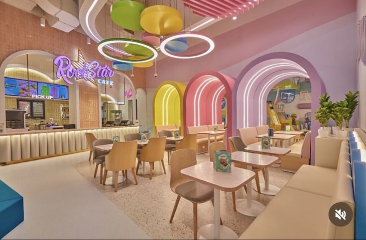 the interior of a colorfully decorated restaurant with circular lights and round tables in pastel colors