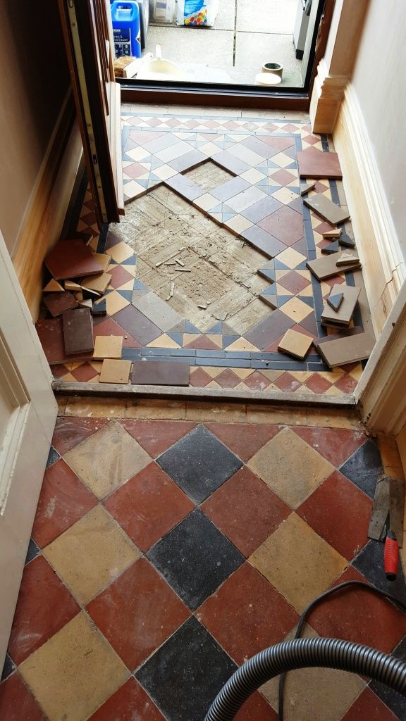 an open door in a room with tile flooring and tools on the ground next to it