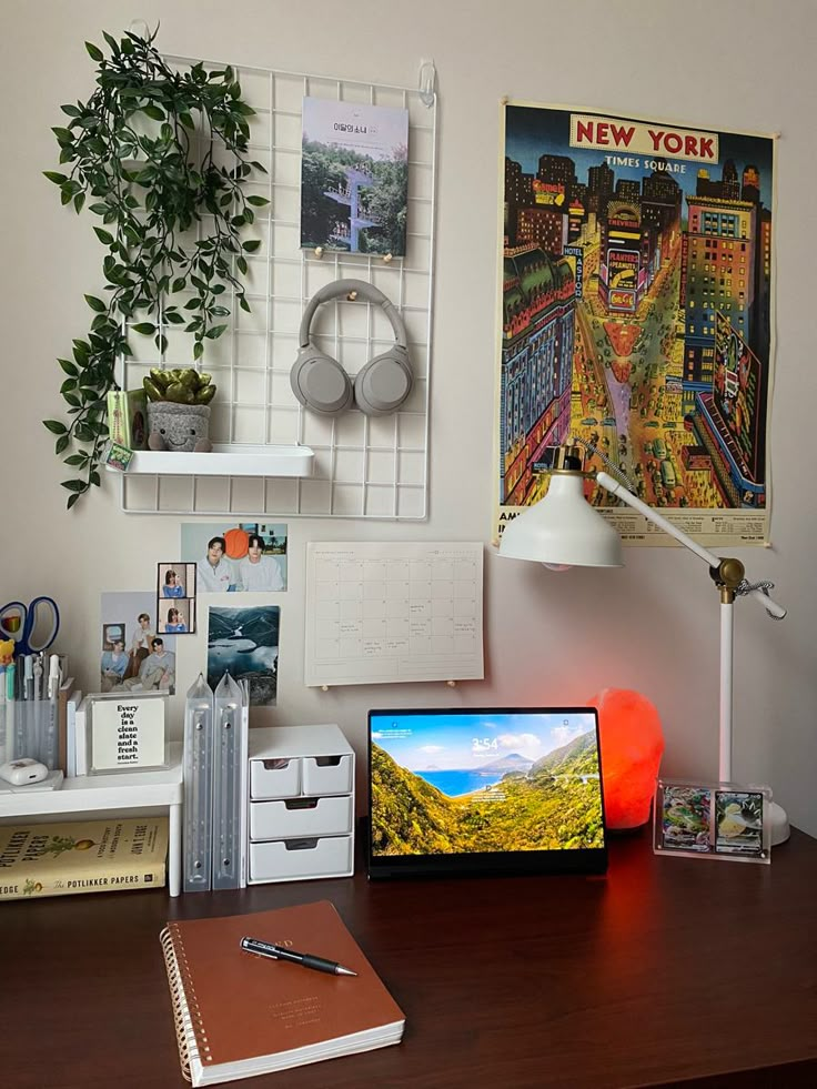 the desk is cluttered with many things and has a laptop computer on it, along with other office supplies