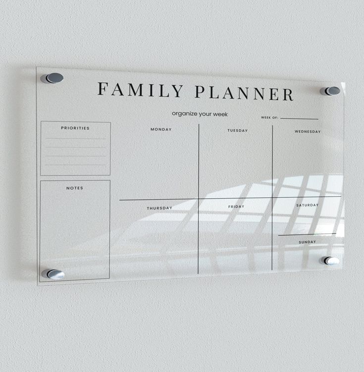 a family planner hanging on the wall in front of a white wall with metal brackets