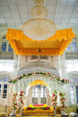 the interior of a large building decorated in yellow and white flowers, with a chandelier hanging from the ceiling