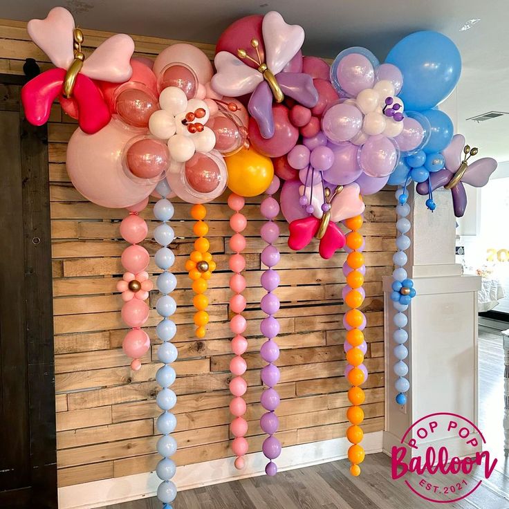 balloons and streamers are hanging from the wall in front of a wood paneled wall