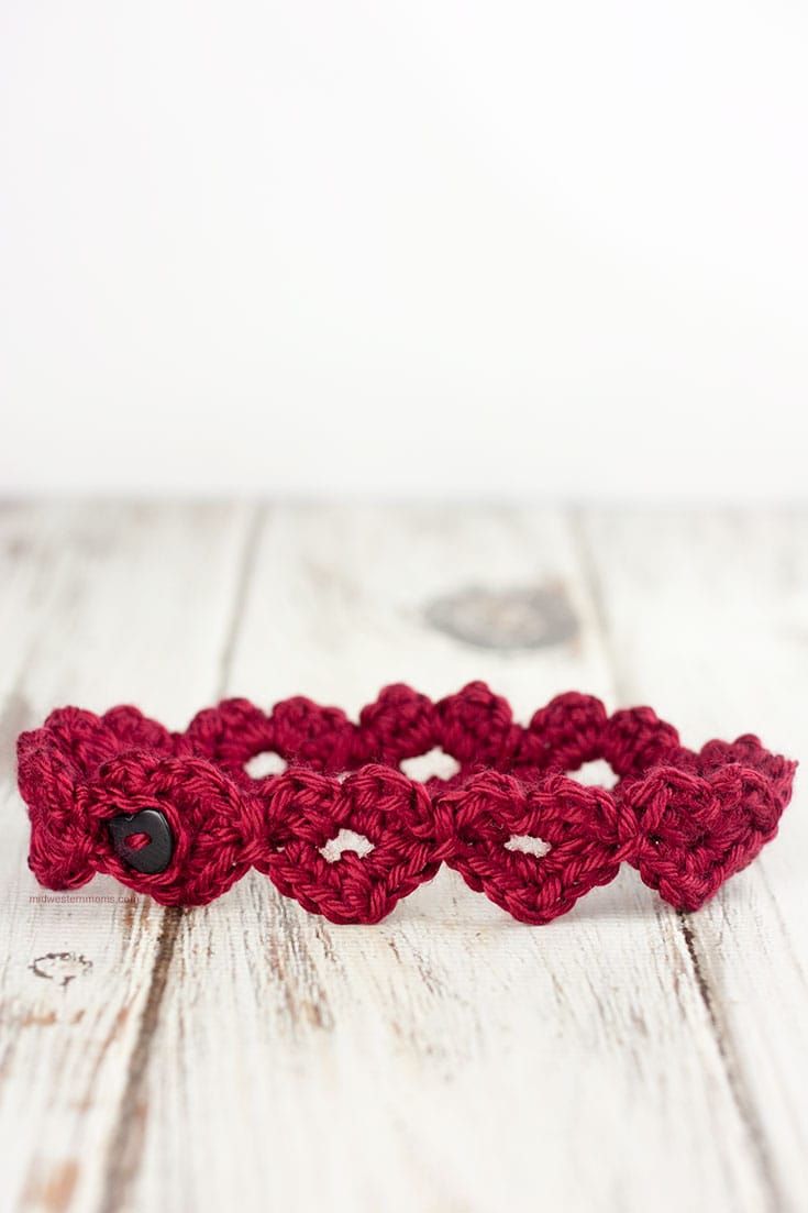 two crocheted hearts are sitting on a wooden surface