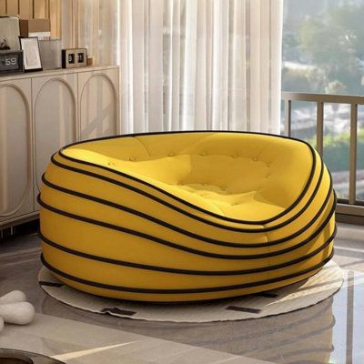 a yellow bean bag chair sitting on top of a floor next to a dresser and window