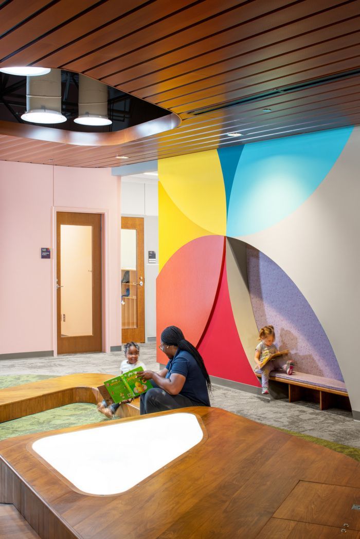 a person sitting on the ground reading a book in front of a large colorful wall