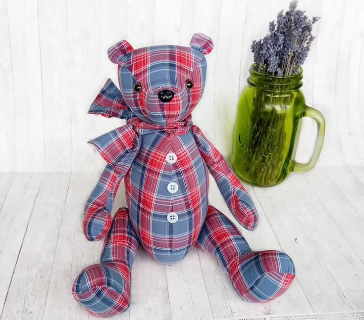 a blue and red plaid teddy bear sitting next to a mason jar with lavender in it