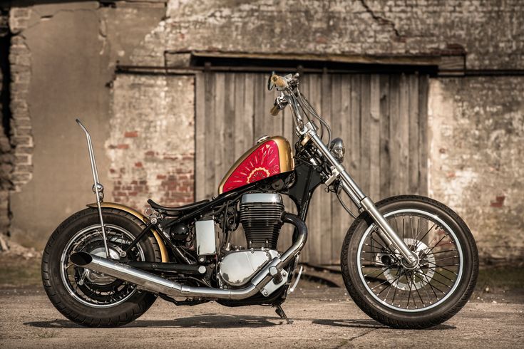 a black and gold motorcycle parked in front of an old building with graffiti on it