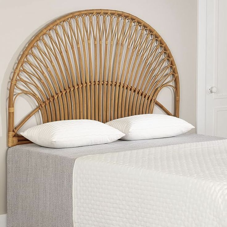 a wicker headboard with two pillows on top of it in a white bedroom