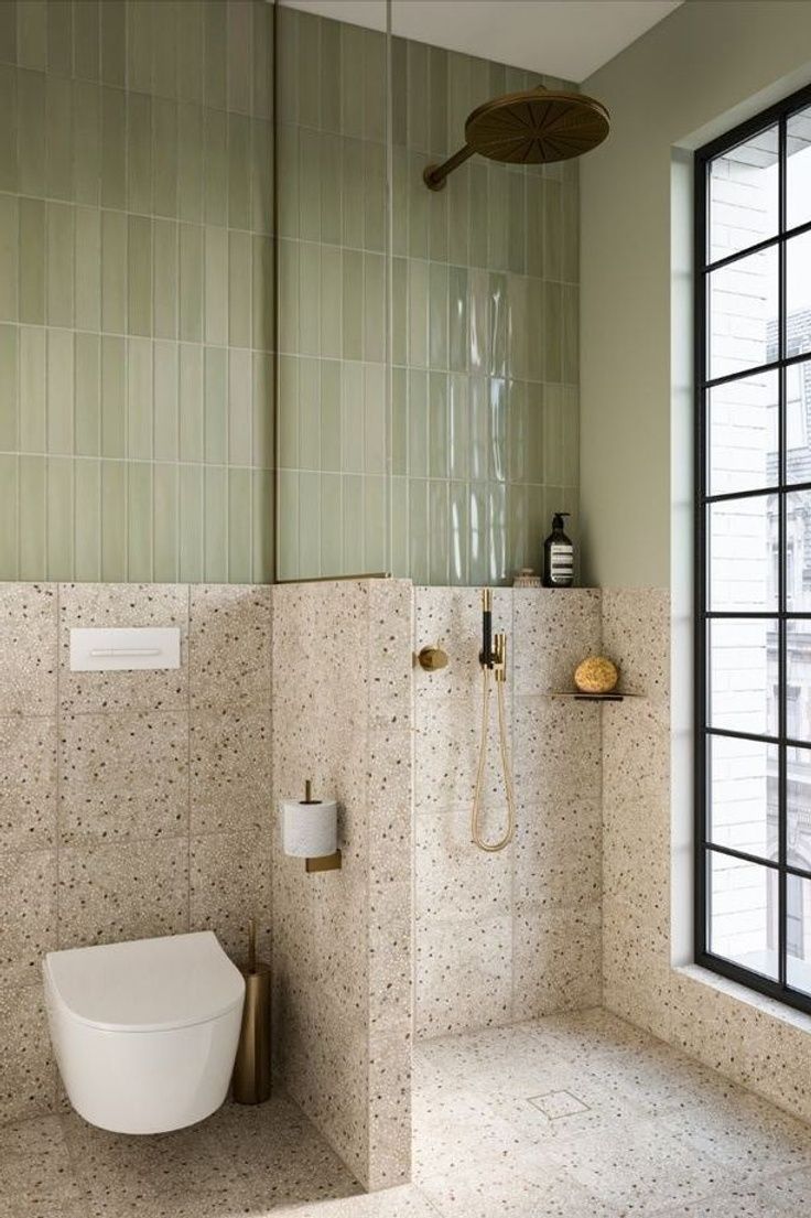 a bathroom with a toilet, shower and window in the corner next to it's tiled walls