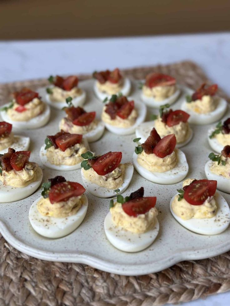 deviled eggs topped with bacon and garnish on a platter