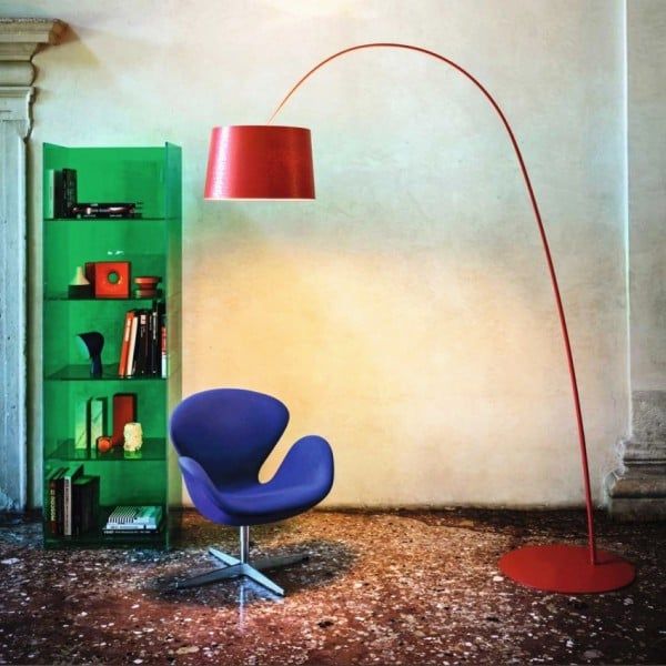 a blue chair sitting next to a green book shelf and a red lamp on top of it