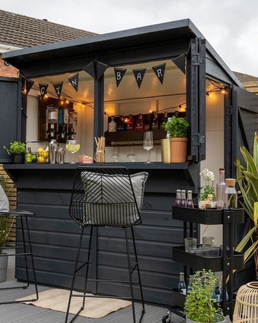 an outdoor bar with chairs and tables in front of it, surrounded by potted plants