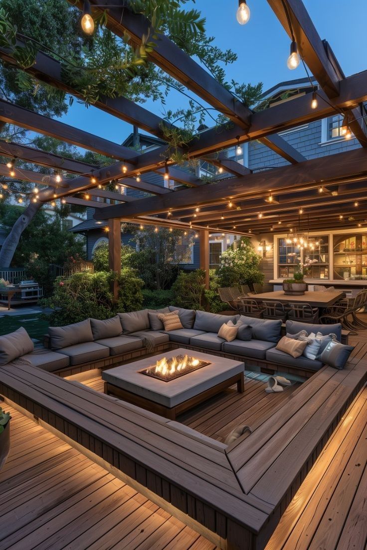 an outdoor living area is lit up with string lights and fire pit in the middle